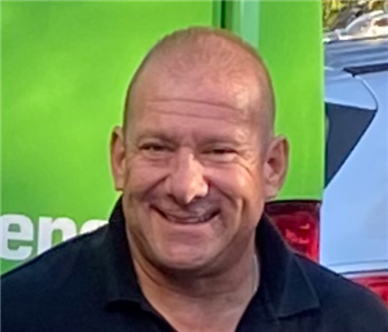 Man in a black SERVPRO polo smiling 