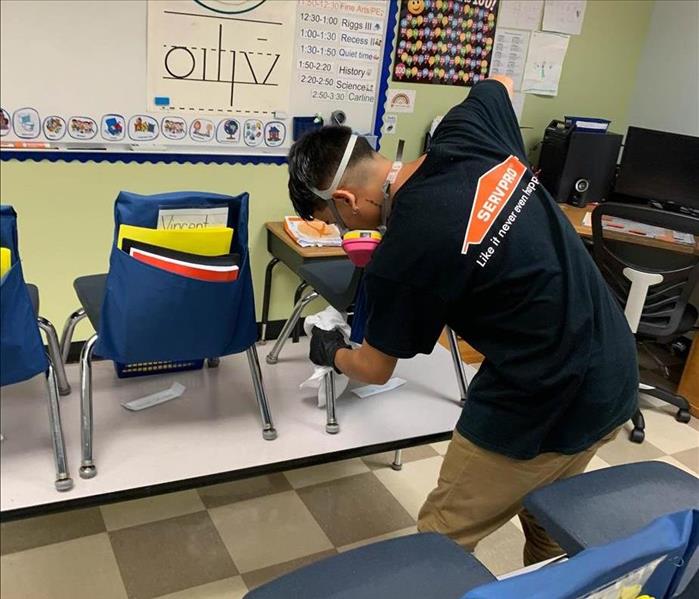 Team member cleaning chairs in classroom.