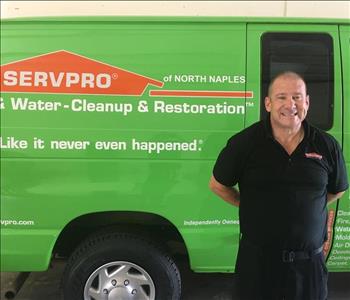 Man in a SERVPRO black polo standing in front of a green truck.