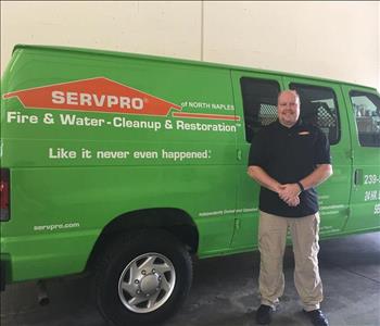 Tall man standing in front of a green SERVPRO truck.